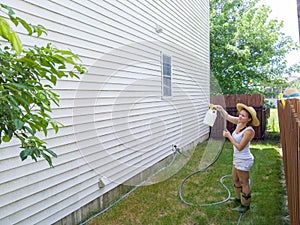 Capable fit woman spraying down house sidings photo