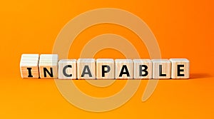Capable or incapable symbol. Concept words Capable or Incapable on wooden cubes. Beautiful orange table orange background.