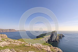 A cape extending to the sea and a light house at the point end.