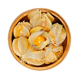 Cape gooseberries with partly open calyx, in a wooden bowl