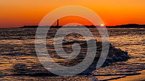 The Cape May Point Lighthouse and waves on the Atlantic at sunset, seen from Cape May, New Jersey.