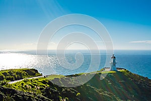 Cape Reinga Lighthouse with azure surface of calm ocean behind. Famous tourist attraction at Cape Reinga, Far North, New