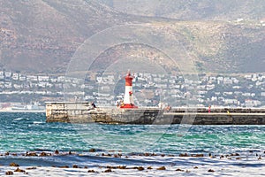 View from St James beach over Kalk Bay recreational harbour and breakwater lighthouse built in 1919  in |False Bay, Cape Town