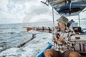caped angler using cell phone with finger pointing on boat photo