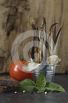 Capelin cold smoked fish in a decorative bucket on a black and o