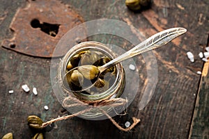 Capers on wooden background. Edible flower buds of Capparis spinosa, caper bush or Flinders rose. close up. top view