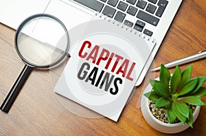 Capital gains - increase in a capital asset's value and is realized when the asset is sold, text concept on notepad