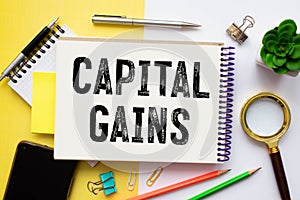 Capital gains - increase in a capital asset's value and is realized when the asset is sold, text concept on notepad