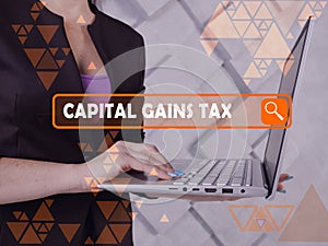 CAPITAL GAINS TAX phrase on the screen. Loan officer use internet technologies at office. Concept search and CAPITAL GAINS TAX