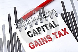 CAPITAL GAINS TAX text on notebook on chart with pen photo