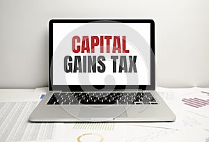 Capital gains tax word on laptop with charts