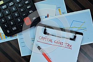 Capital Gains Tax write on a paperwork isolated on Wooden Table