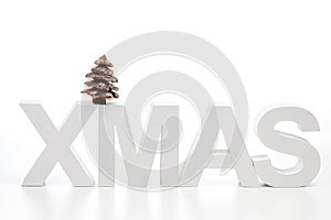 Capital letters forming the word xmas on top chocolate christmas tree against white background