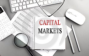 CAPITAL MARKETING text on notepad on chart with keyboard and calculator on grey background