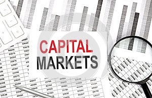 CAPITAL MARKETS text on document with pen,graph and magnifier,calculator