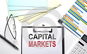 CAPITAL MARKETS text on paper sheet with chart,color paper and calculator