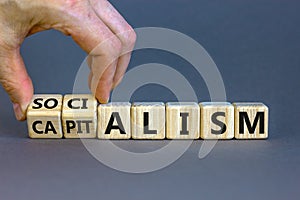 Capitalism or socialism. Hand turns cubes and changes word `capitalism` to `socialism`. Beautiful white background, copy space