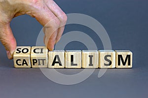 Capitalism or socialism. Hand turns cubes and changes word `capitalism` to `socialism`. Beautiful white background, copy space photo