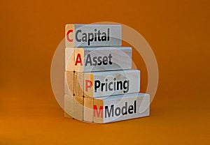 CAPM capital asset pricing model symbol. Concept words CAPM capital asset pricing model on blocks on a beautiful orange background photo