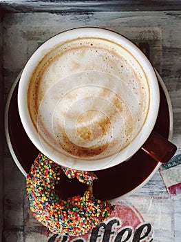 Cappuccino and bitten donut on a tray