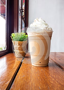 Cappuccino blend in plastic cup. Served on wooden table in cafe. Favorite menu of caffeine beverage