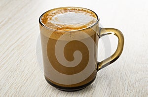 Cappuccino in brown cup on wooden table