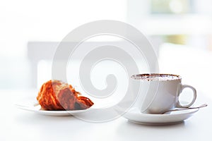 Cappuccino coffee and croissant on white background