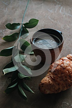 Cappuccino coffee and croissant on wooden background on the table. Perfect breakfast in the morning