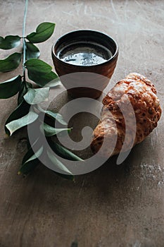 Cappuccino coffee and croissant on wooden background on the table. Perfect breakfast in the morning. Rustic candid style