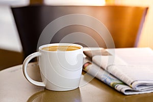 Cappuccino coffee cup on wooden table with newspaper