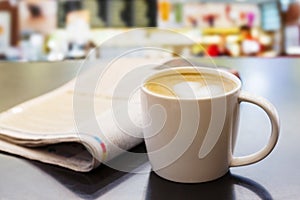 Cappuccino coffee cup on wooden table with newspaper