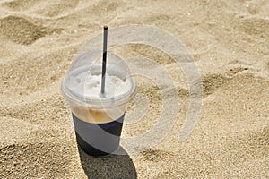 cappuccino coffee with straw on the beach