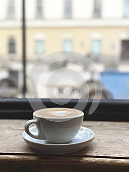 Cappuccino coffee in white cup on wooden table