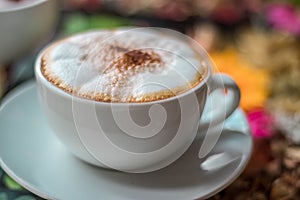 Cappuccino coffee on wooden table and sunlight background