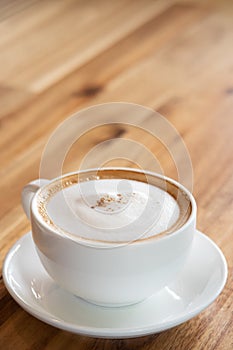 Cappuccino coffee on wooden table with text space