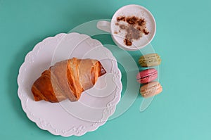 Cappuccino with croissant and macarons photo