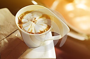 Cappuccino cup in coffee shop with gradient sunlights