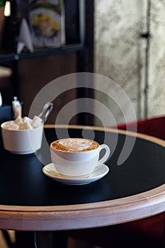 Cappuccino cup of coffee with sugar on the table in restaurant side view and a lot of copy space. Coffee cup latte and