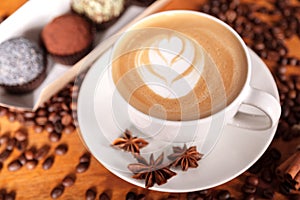 Cappuccino Cup with latte art on a wooden table with coffee beans, anise, cinnamon. Spending time with a Cup of coffee