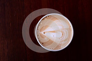 Cappuccino in a disposable Cup top view. Heart on the foam of coffee