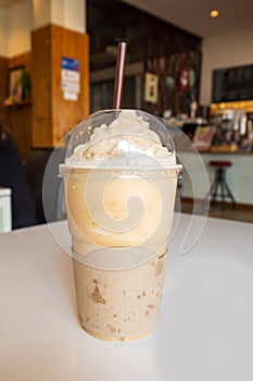 Cappuccino frappe in plastic cup. On wooden table in cafe. photo