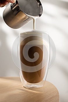 Cappuccino in a glass cup on a wooden table, Coffee and froth milk