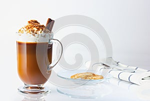 Cappuccino in a glass, Irish glass, cinnamon stick, ground nut and chocolate chips. Halved oatmeal cookies in a glass plate. Coffe