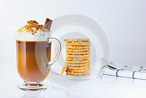 Cappuccino in a glass, Irish glass, cinnamon stick, ground nut and chocolate chips. Halved oatmeal cookies in a glass plate. Coffe