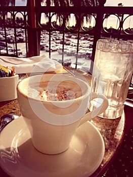 Cappuccino and glass of water on the table