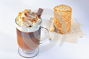 Cappuccino in an Irish glass goblet, whipped cream, ground nut and chocolate chips. Cinnamon stick. Oatmeal cookies on a paper nap