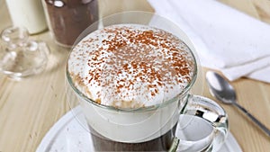 Cappuccino or latte in cup. White froth milk is sprinkled with ground cinnamon and cocoa powder. Dessert drink decoration. Instant