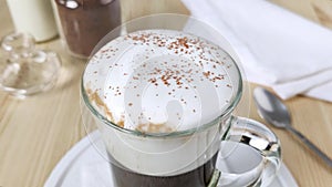 Cappuccino or latte in cup. White froth milk is sprinkled with ground cinnamon and cocoa powder. Dessert drink decoration. Instant
