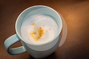Cappuccino in a pastel blue cup on a brown table, visible white coffee foam
