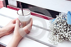 Cappuccino in a white ceramic cup and saucer on a white wooden bench